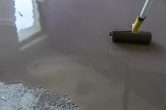 Chantier intérieur, application de revêtement de sol liquide gris sur surface plane