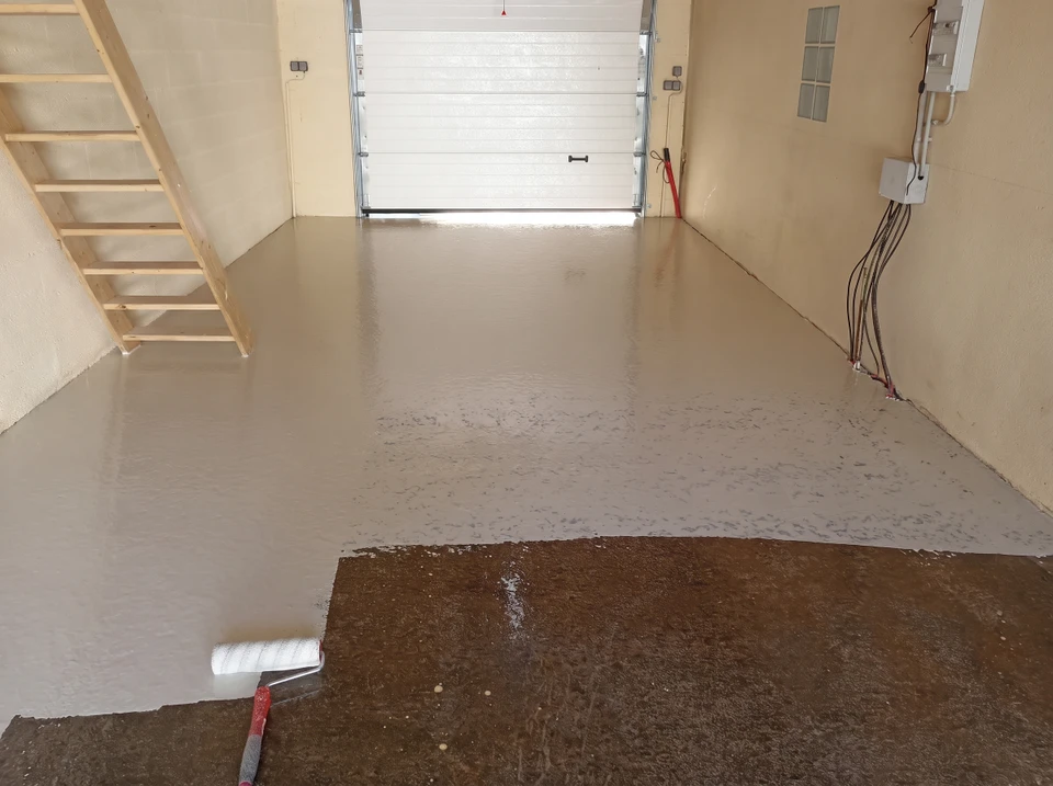 Garage en cours d'application d'un revêtement époxy gris sur sol béton