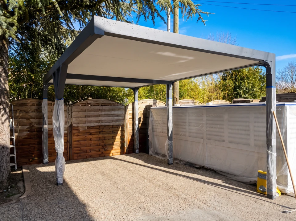 Pergola bioclimatique aluminium anthracite en cours d'installation dans un jardin