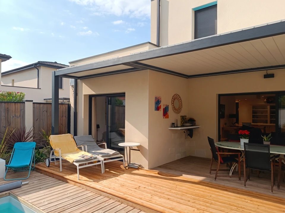 Terrasse couverte moderne avec pergola bioclimatique en aluminium anthracite, adossée à une maison contemporaine