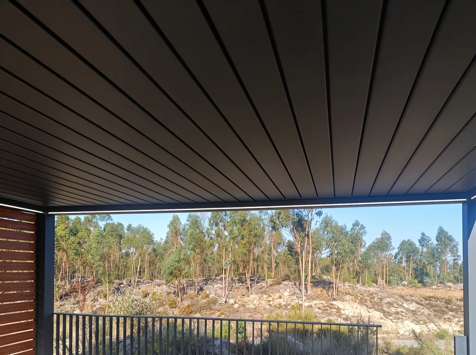 Pergola bioclimatique vue de l'intérieur, lames orientables en aluminium laqué anthracite formant un toit fermé
