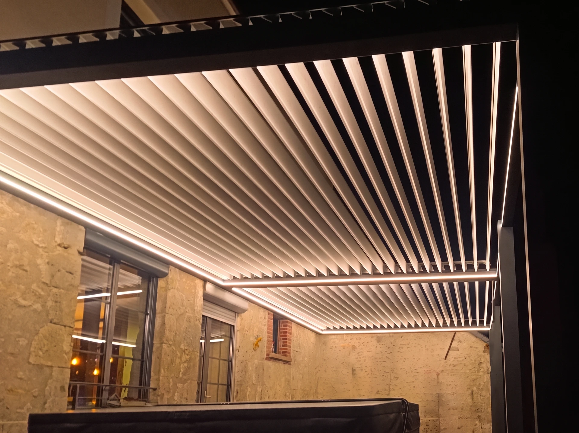 Pergola bioclimatique moderne avec lames orientables en aluminium blanc partiellement ouvertes