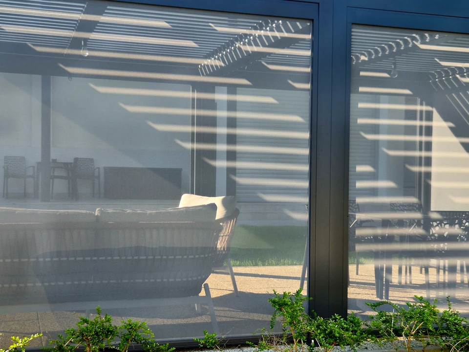 Pergola bioclimatique à lames orientables en aluminium blanc, éclairée de nuit par des bandeaux LED intégrés dans les rails périmétriques