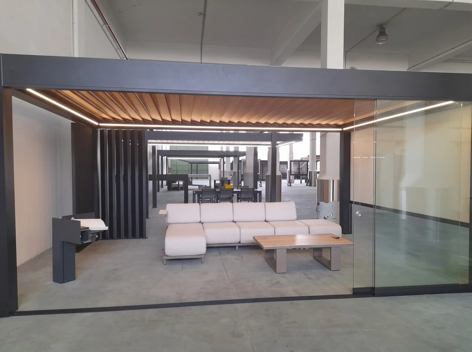Garage moderne extérieur avec porte à enroulement en aluminium anthracite RAL 7016, structure portante en profilés aluminium thermolaqué, bardage en bois composite horizontal, toiture plate avec verrière polycarbonate translucide
