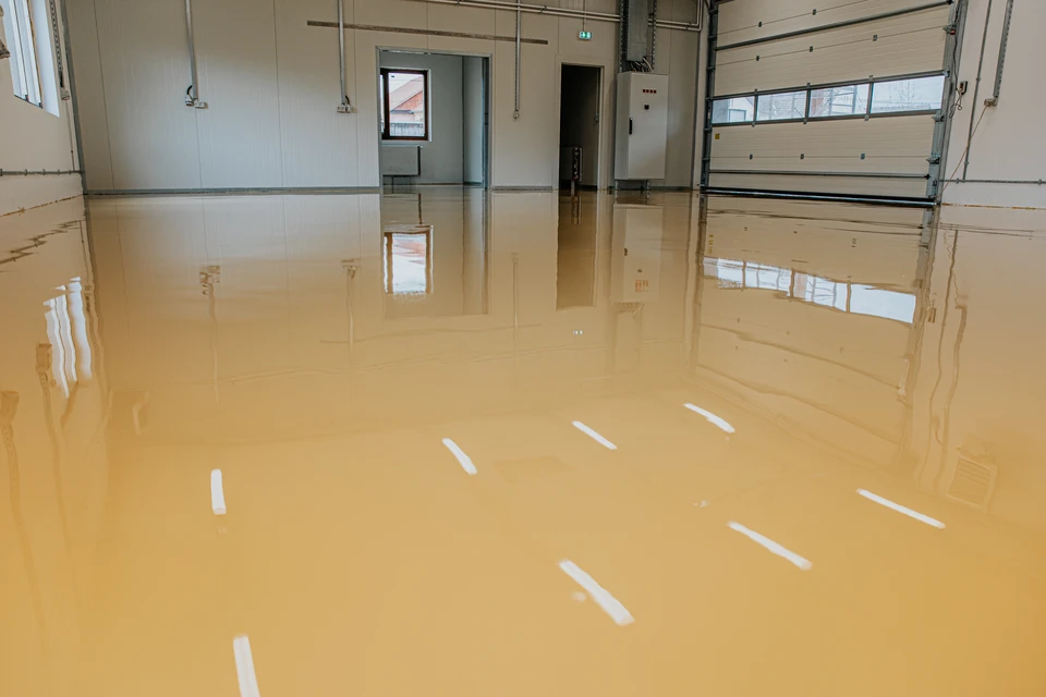 Garage en cours d'application d'un revêtement époxy gris sur sol béton